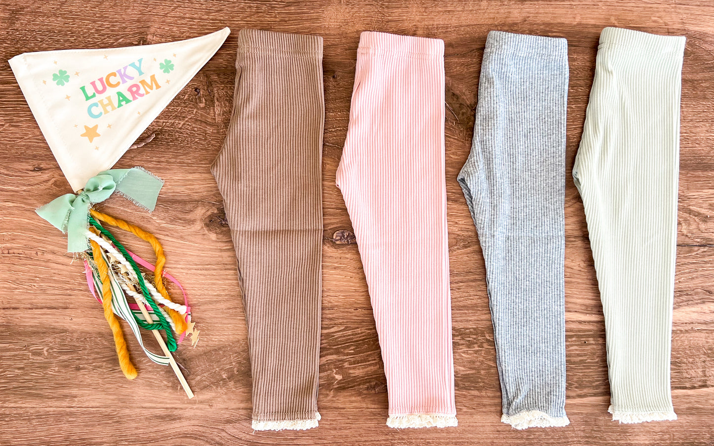 A set of lace-top ribbed leggings in beige, pink, gray, and green, displayed flat with a lace trim visible at the waist.