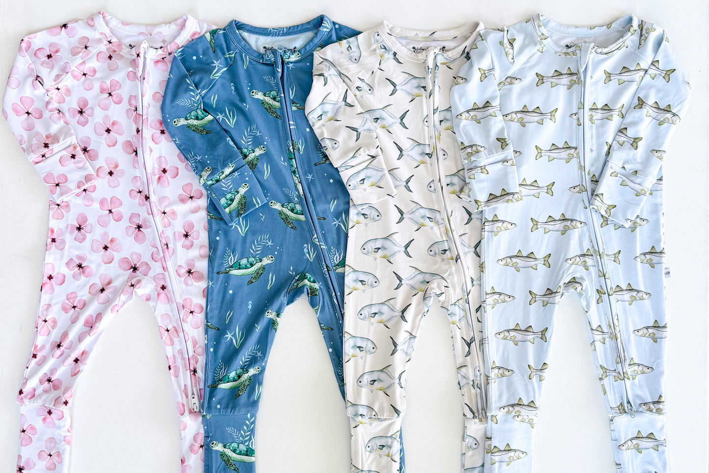 Four children's zippy pajamas onesies with different patterns on a white background