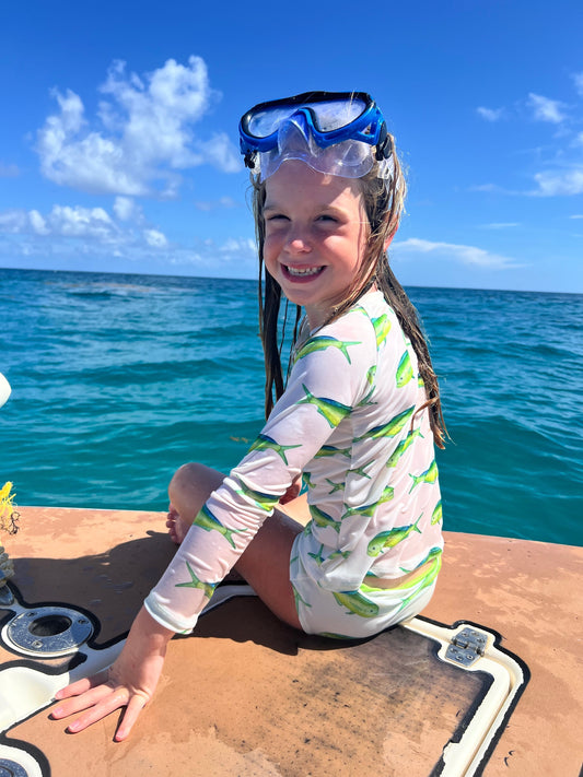 Picture of a girl on a boat wearing a snorkel mask and a mahi mahi long sleeve bathing suit. 