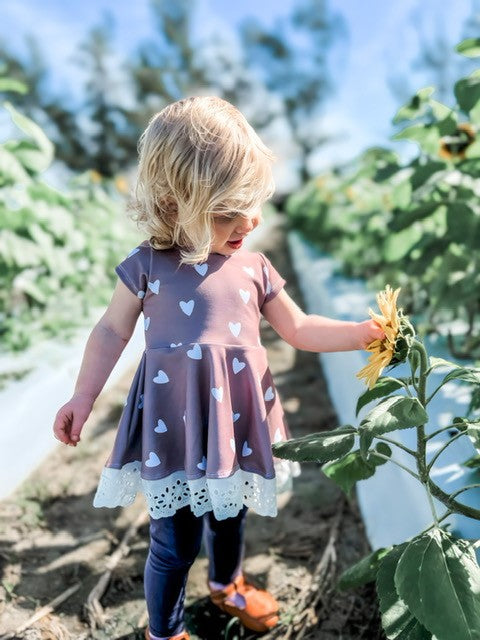 Picture of a little girl standing in a sunflower patch wearing a heart peplum