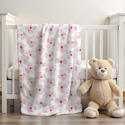 Floral-patterned blanket draped over a crib with a teddy bear beside it.