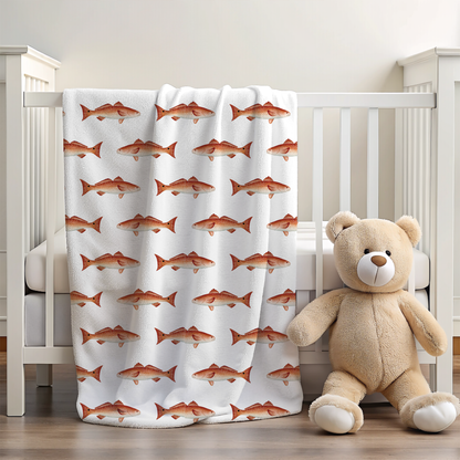 Crib with a  redfish-patterned blanket and a teddy bear on a wooden floor.