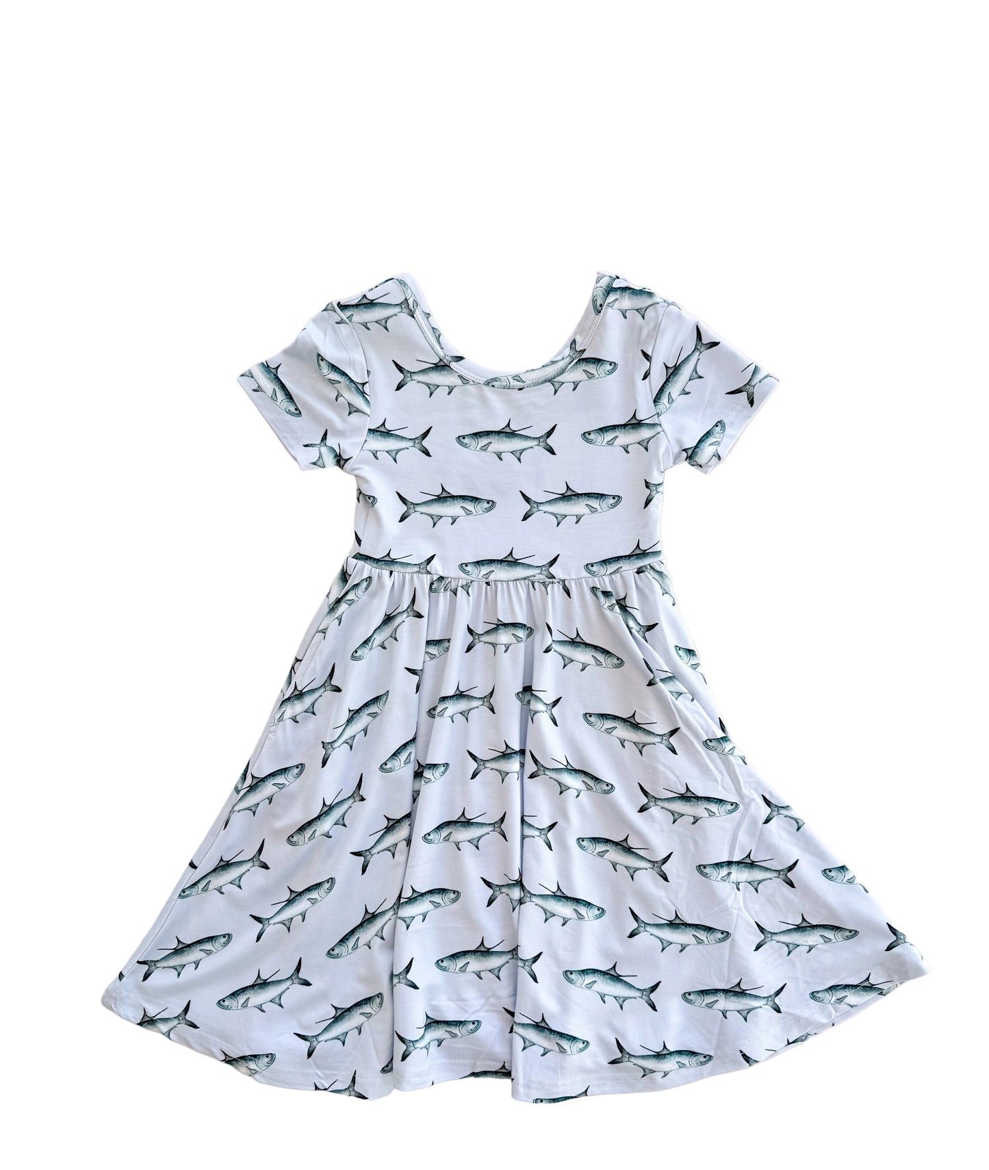 Flat lay of short sleeved, twirl dress with light blue background and blue tarpon and pockets