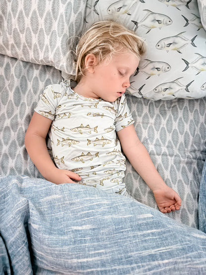 Customer provided photo of a little girl sleeping in blue sheets, wearing the blue snook pajamas