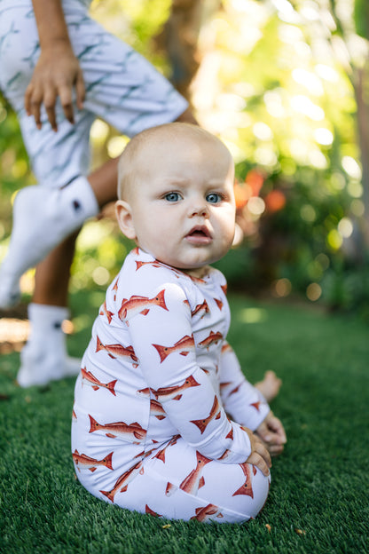 baby wearing a redfish zippy sitting up with legs crossed. Child running through blurred background