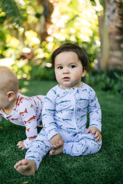 Two children in tarpon and redfish pajamas standing on grass with a blurred natural background