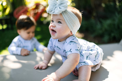 Two babies in matching Tarpon outfits outdoors on a sunny day.