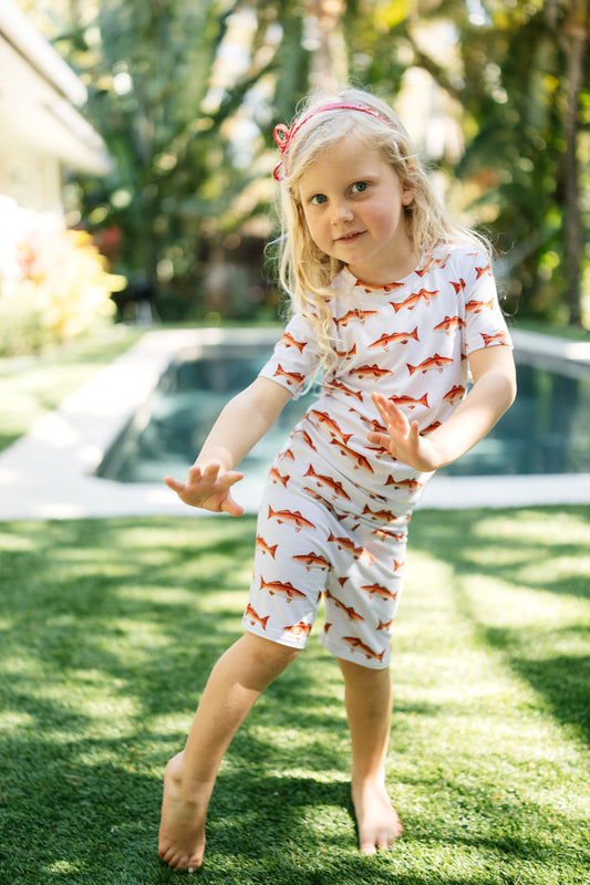 Little girl dancing in her redfish pajamas in front of a pool outdoors