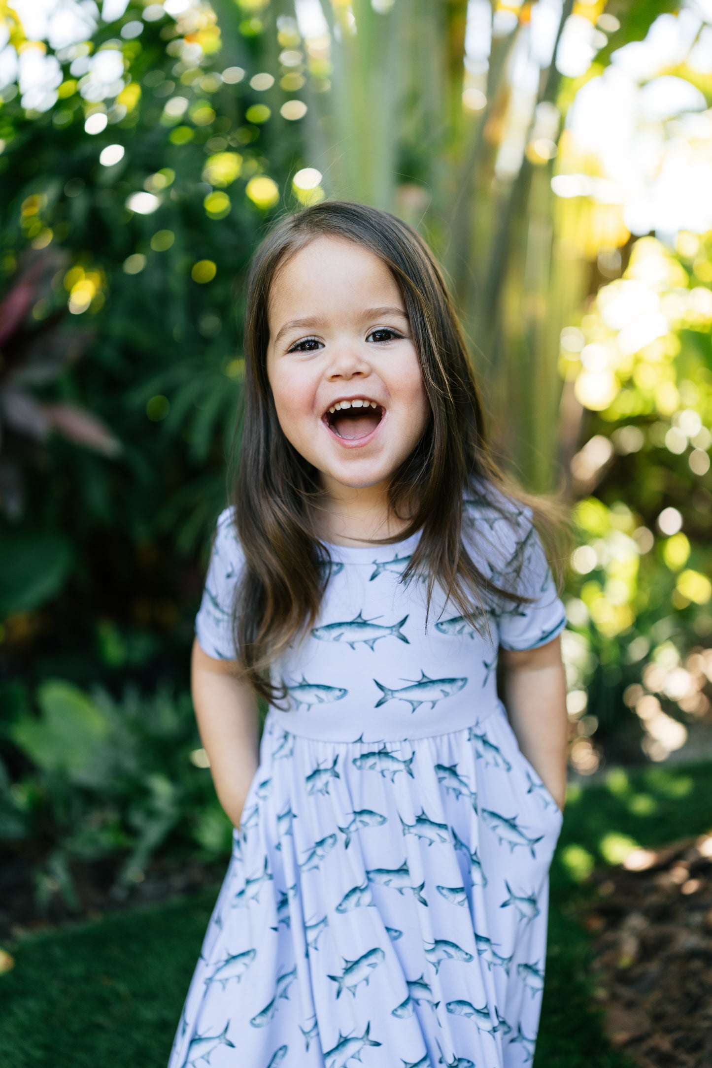 Young girl wearing the tarpon seaside dress with a large smile outdoors