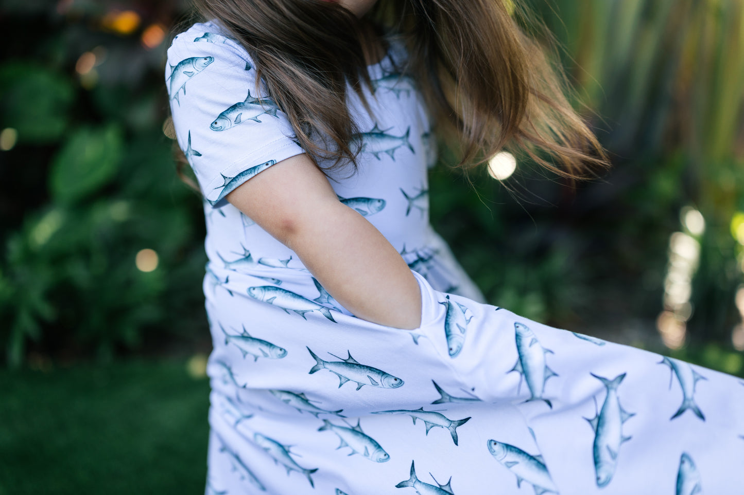 Little girl twirling with her hands in her pockets wearing the tarpon seaside dress