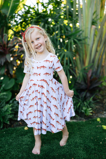 Little girl wearing a redfish seaside dress with a white background outdoors