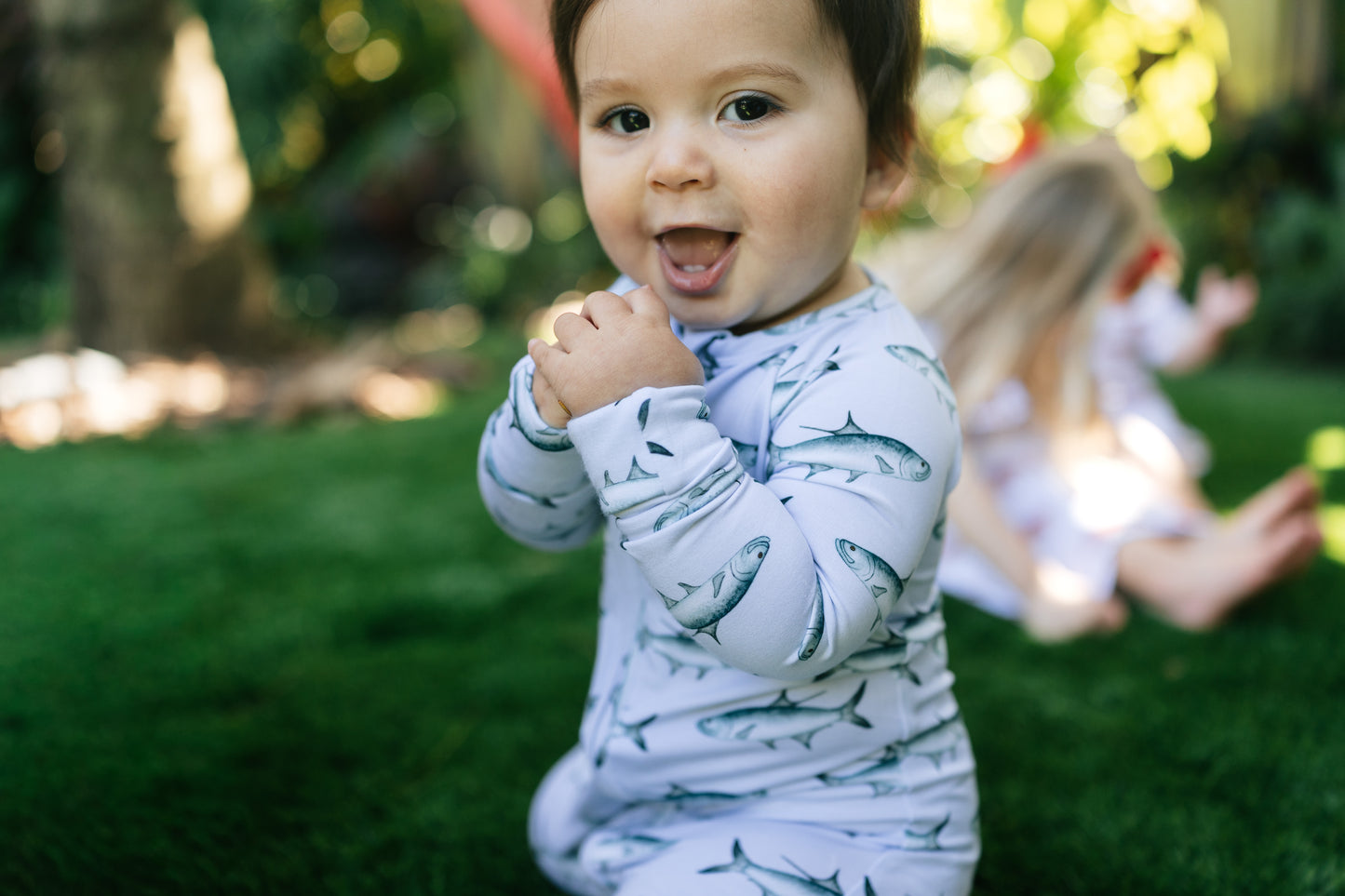 child with an open mouth smile wearing tarpon zippy with blurred children in the background