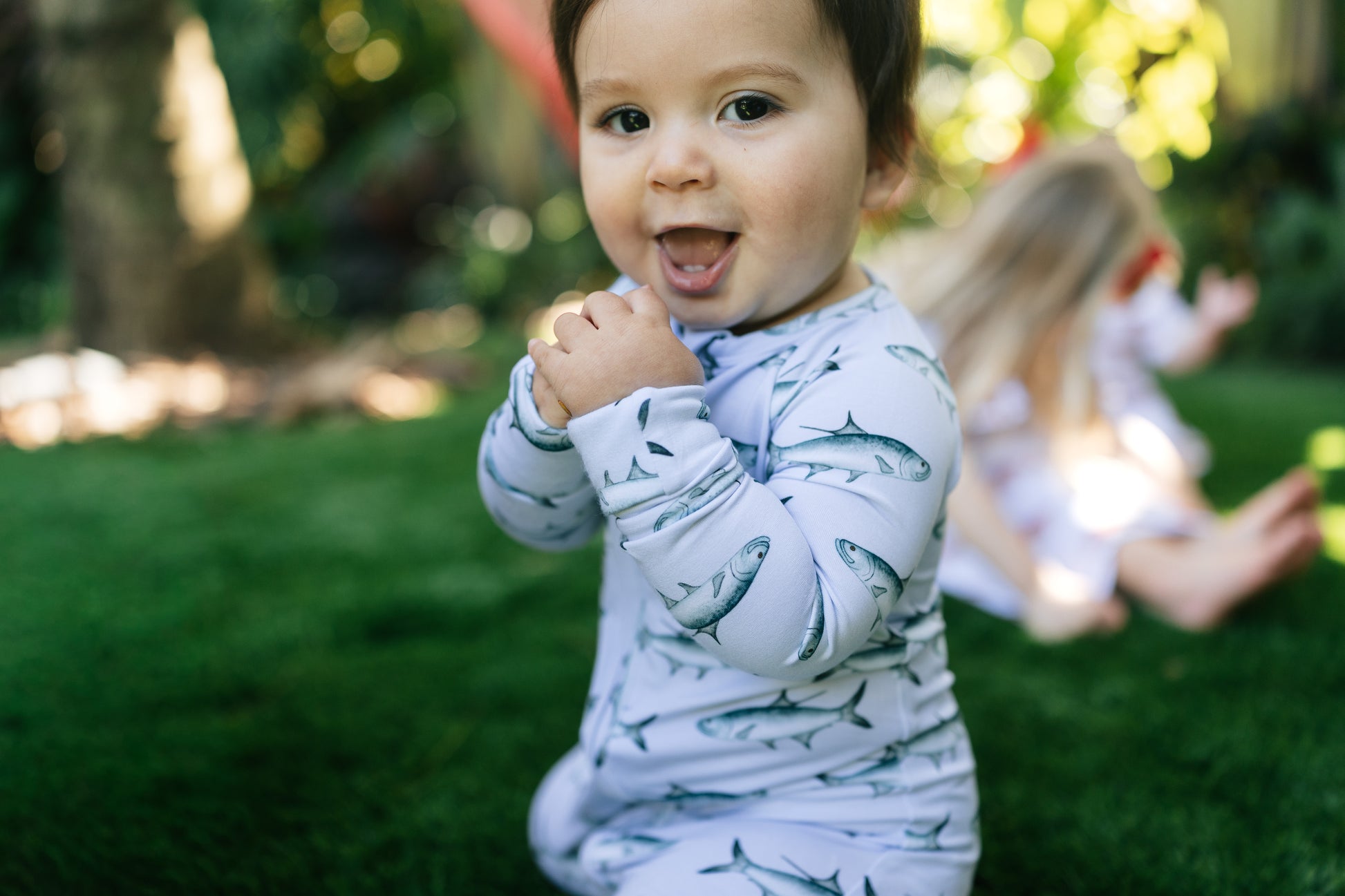 child with an open mouth smile wearing tarpon zippy with blurred children in the background