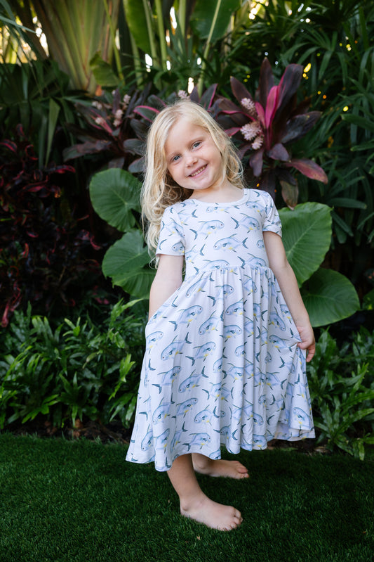 young girl wearing a permit seaside twirl dress with a tropical background