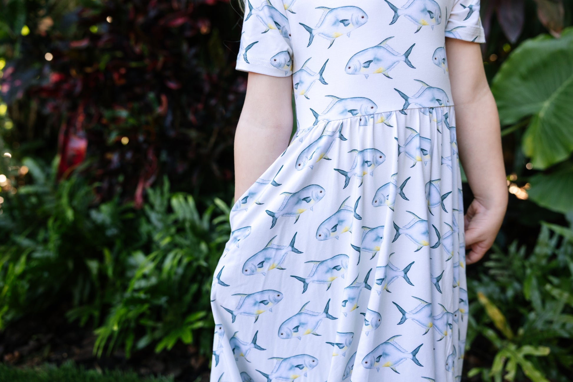 close up of young girl wearing a permit seaside twirl dress with a tropical background