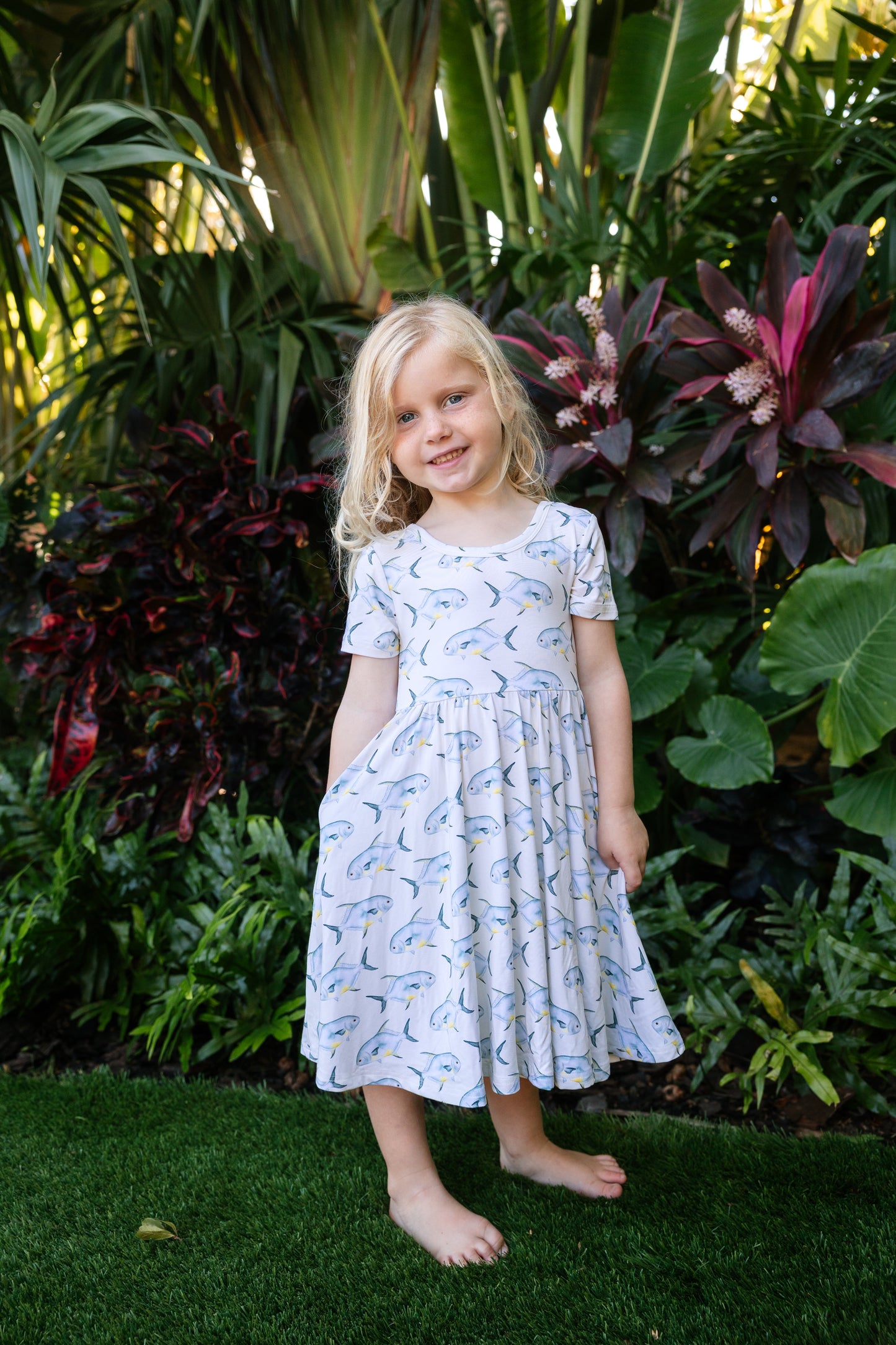 young girl wearing a permit seaside twirl dress with a tropical background