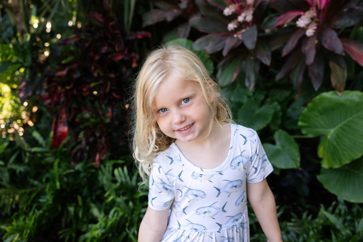 young girl wearing a permit seaside twirl dress with a tropical background