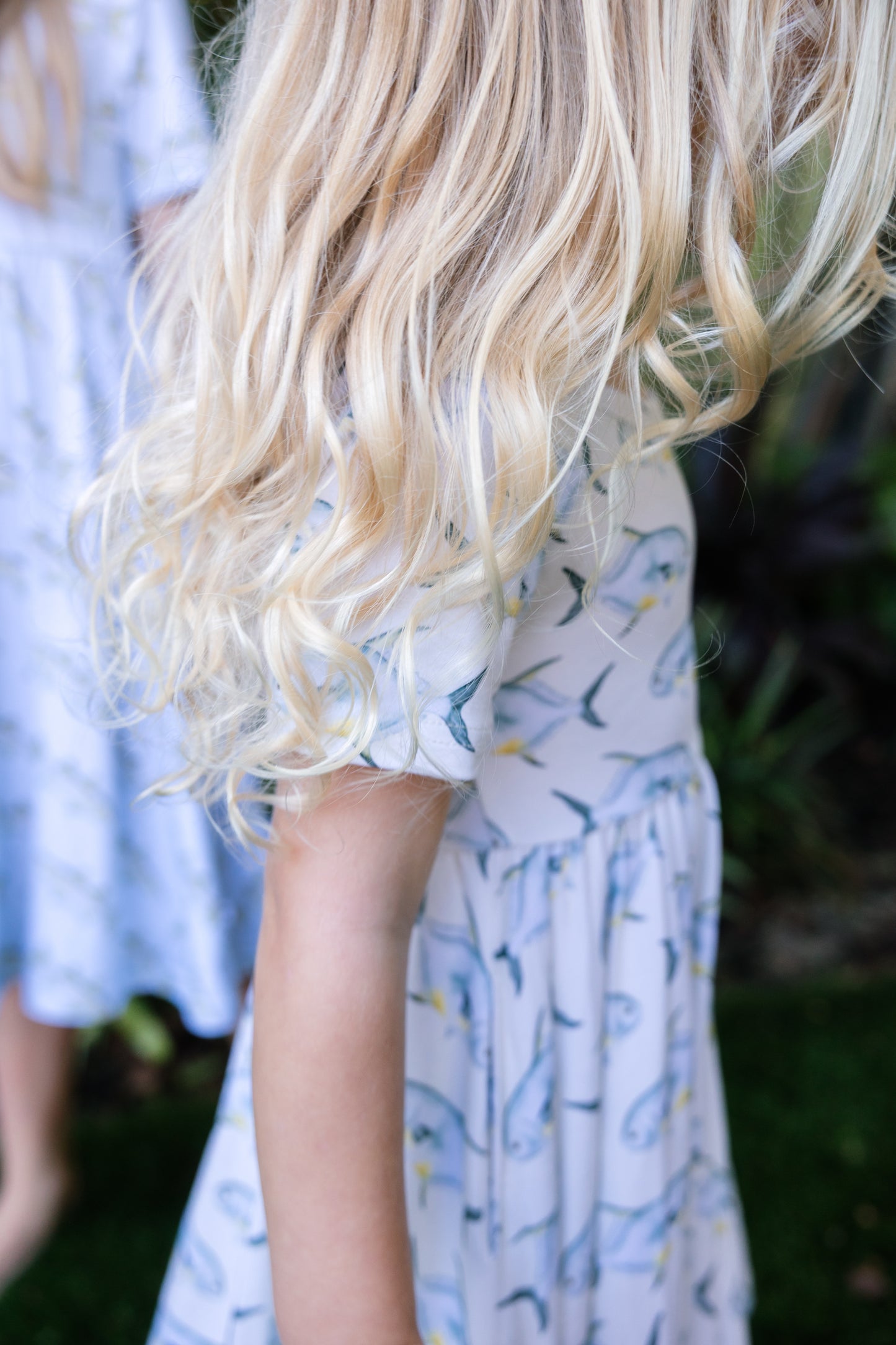 closeup of young girl wearing a permit seaside twirl dress with a tropical background