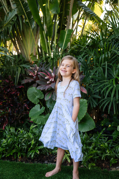 young girl smiling with hands in pockets wearing snook seaside dress