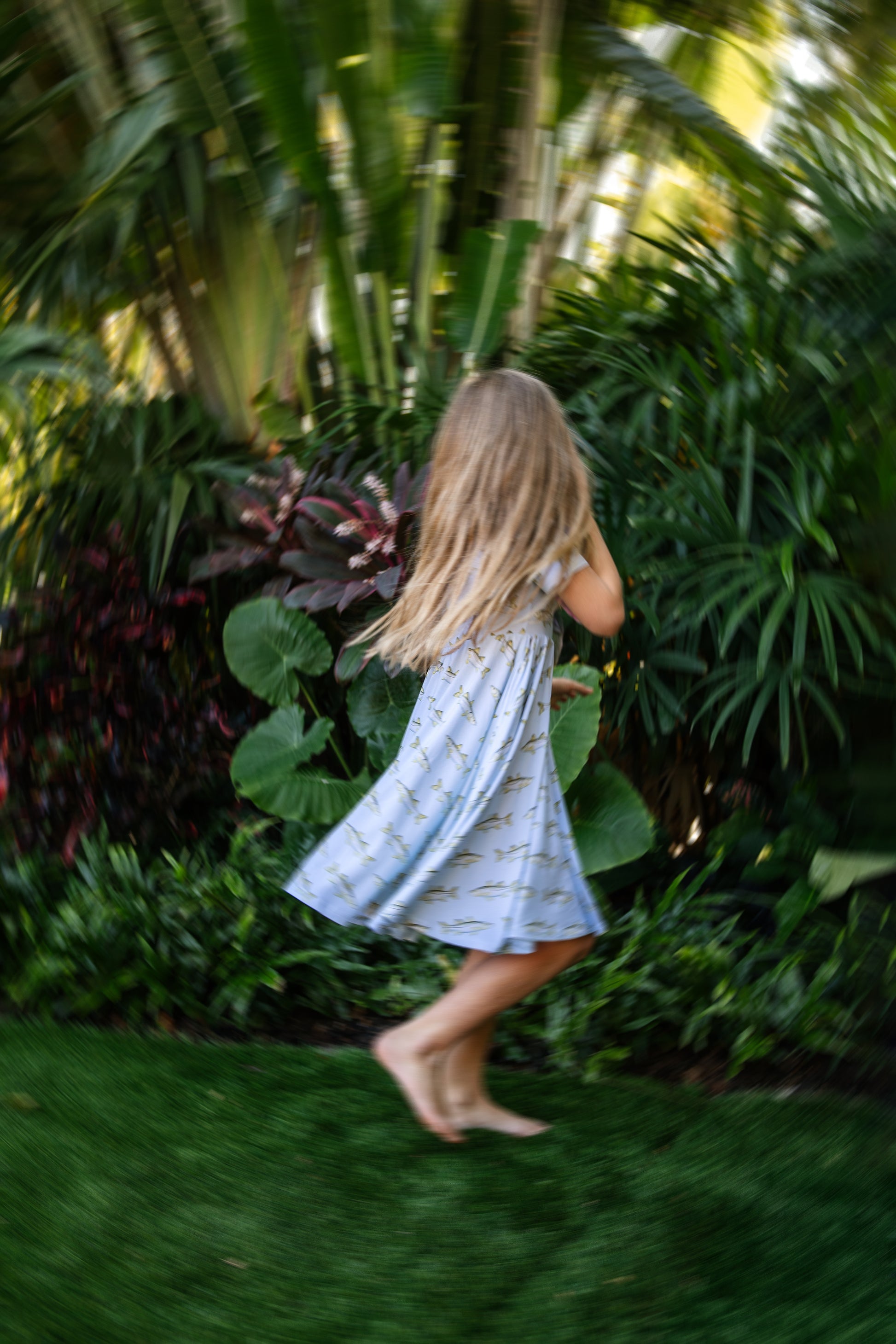 young girl in snook seaside dress twriling with blurred focus