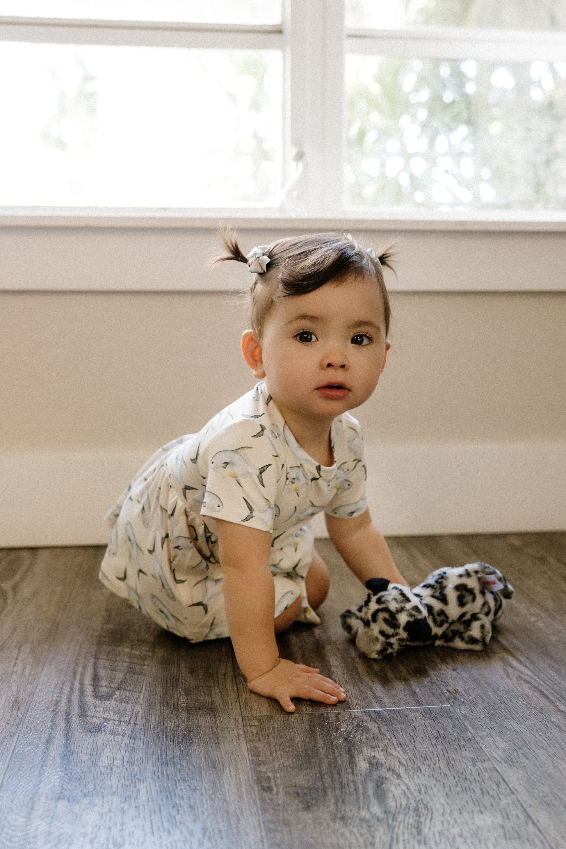 Child sitting on a wooden floor with a window in the background