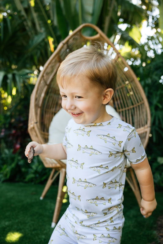 Little boy running through the backyard wearing light, blue snook, pajamas, in short sleeve and short shorts