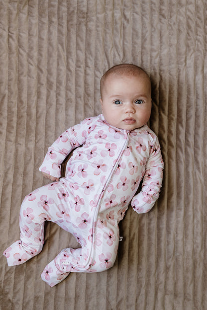 Baby in a pink floral onesie lying on a textured surface