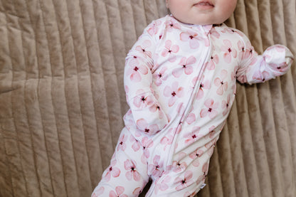 Baby in a pink floral onesie lying on a textured surface