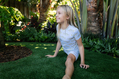 Close-up picture of little girl doing a split with light blue snook, short sleeve pajamas