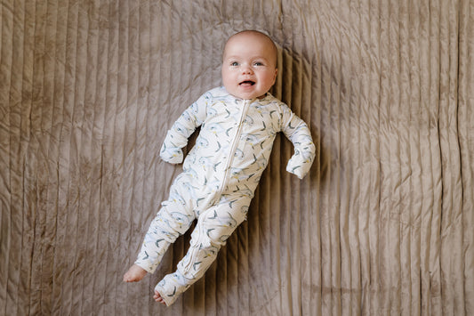  baby wearing the permit zippy laying on a beige blanket