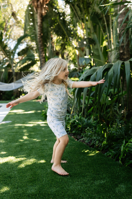 Three year old girl, twirling in the backyard, wearing yellow permits, short sleeve pajamas