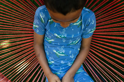 Close-up picture of little boy wearing short sleeve blue pajamas with sea turtles