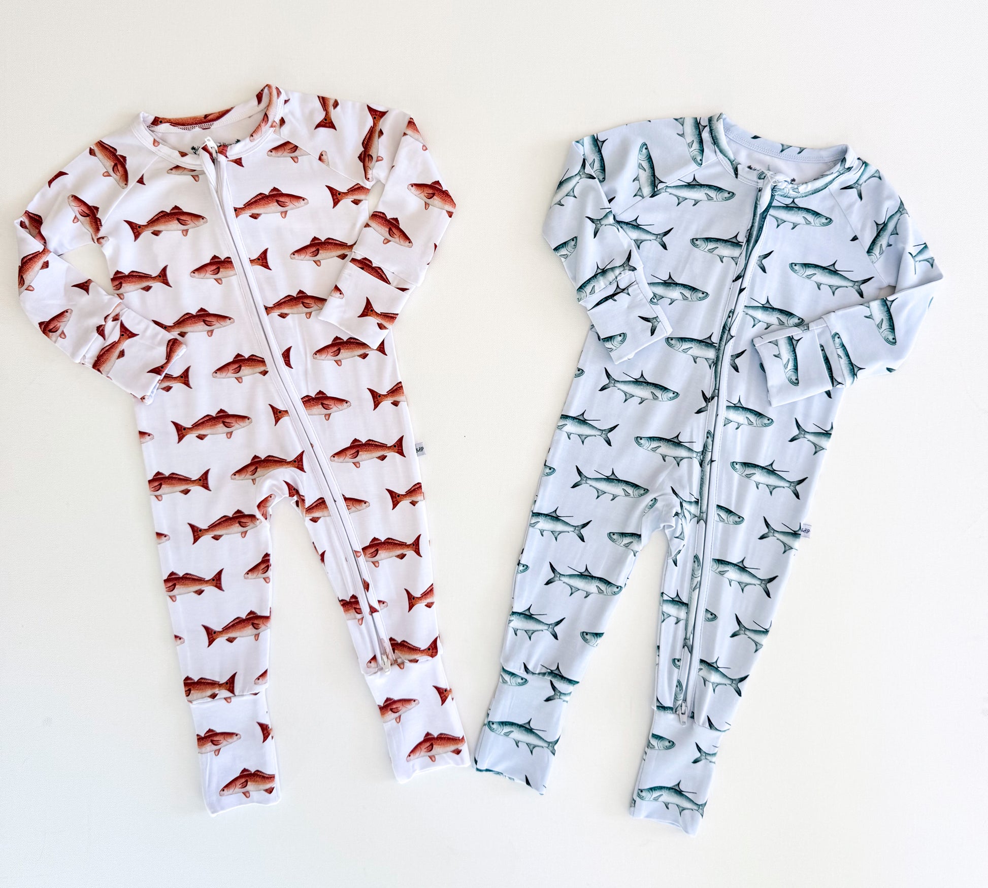 Two baby rompers with and tarpon and redfish patterns on a white background