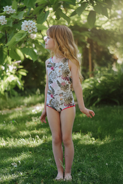 Young girl in a floral swimsuit standing in a garden