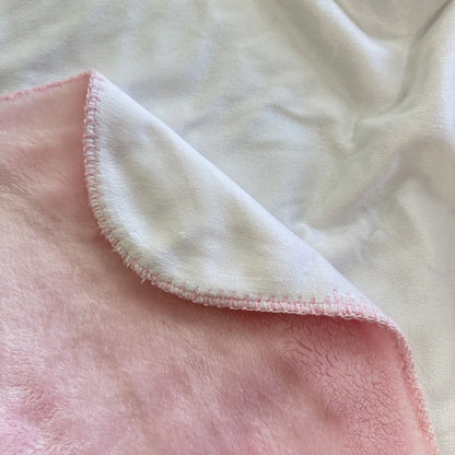 Close-up of white sherpa blanket with pink minky backing