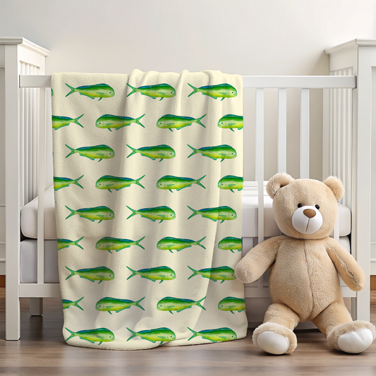 Beige teddy bear sitting on a wooden floor next to a crib with a fish-patterned blanket.