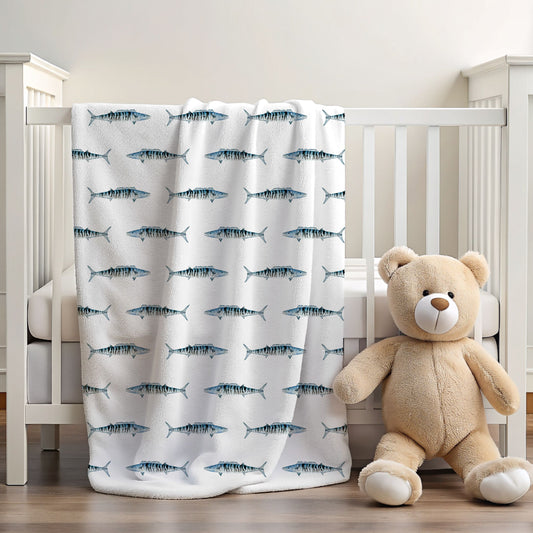 A white crib blanket with a repeating pattern of blue and gray striped fish, draped over a white wooden crib next to a beige teddy bear toy on a wooden floor.